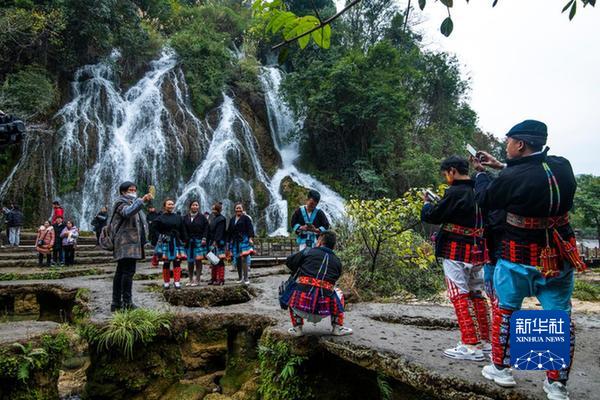 1月22日，游客在荔波县小七孔景区拉雅瀑布前拍照。（何茂强 摄）