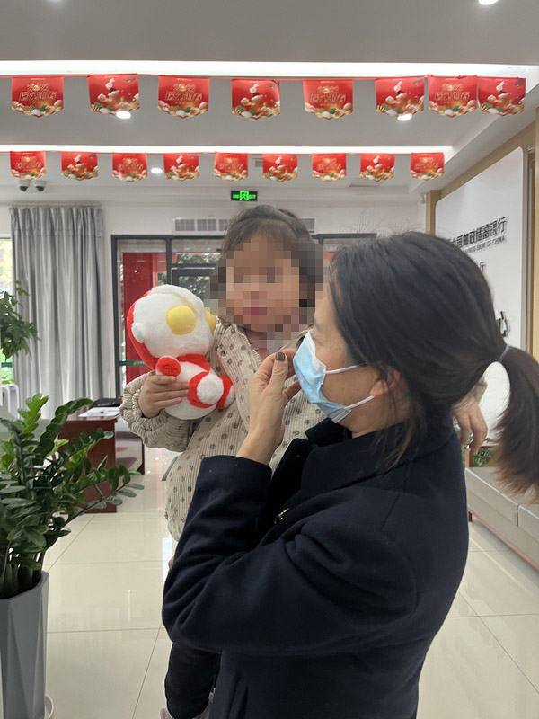 插图二：银行工作人员陪小女孩聊天缓解其紧张情绪。.jpg