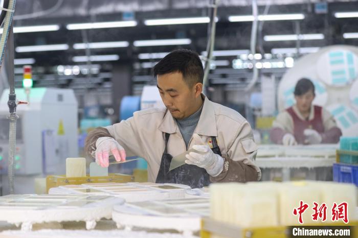 工人将手机屏玻璃盖板放入打磨设备。 瞿宏伦 摄 工人将手机屏玻璃盖板放入打磨设备。 瞿宏伦 摄