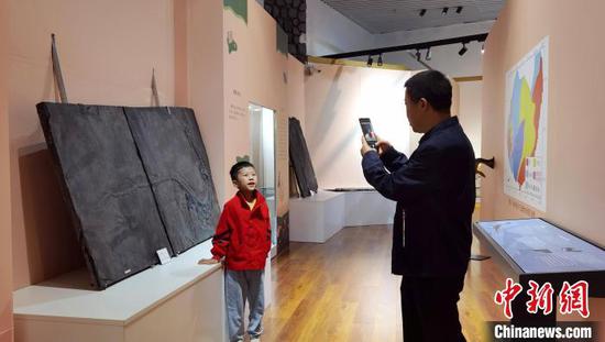 图为参观展览的民众与贵州龙化石合影拍照。周燕玲 摄 图为参观展览的民众与贵州龙化石合影拍照。周燕玲 摄